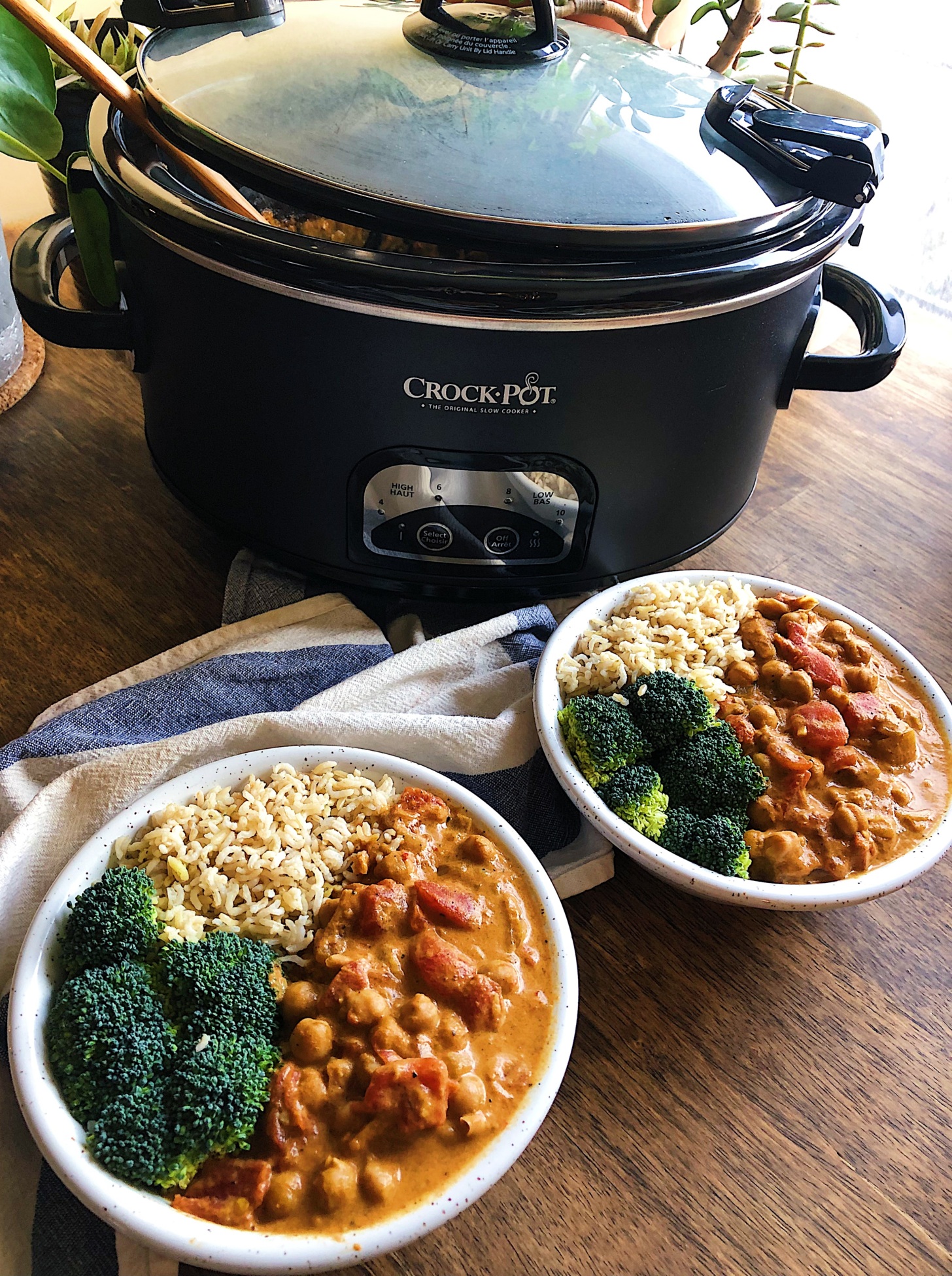 Two bowls of vegan butter chickpeas with a crockpot in the background.