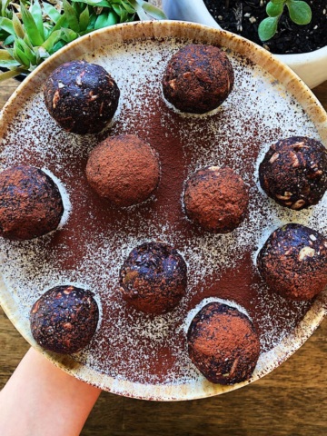 A plate of protein balls on a plate sprinkled with chocolate.