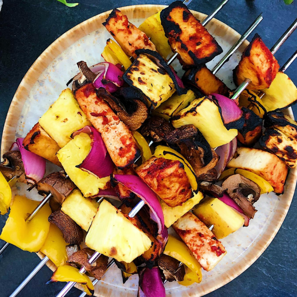 Plate of pineapple BBQ tofu skewers with homemade BBQ sauce on the side