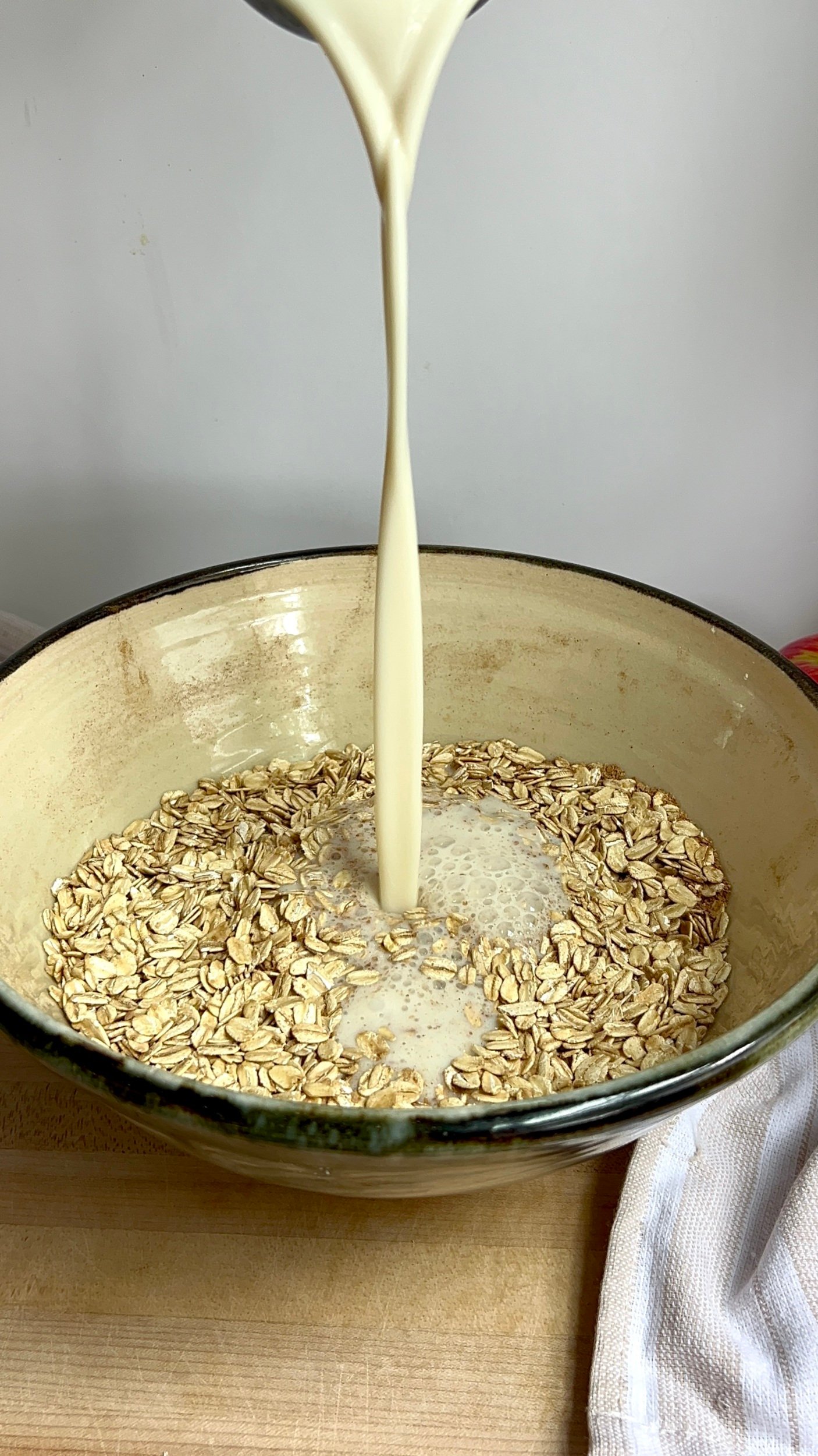 Large bowl with oats and soy milk being poured in.
