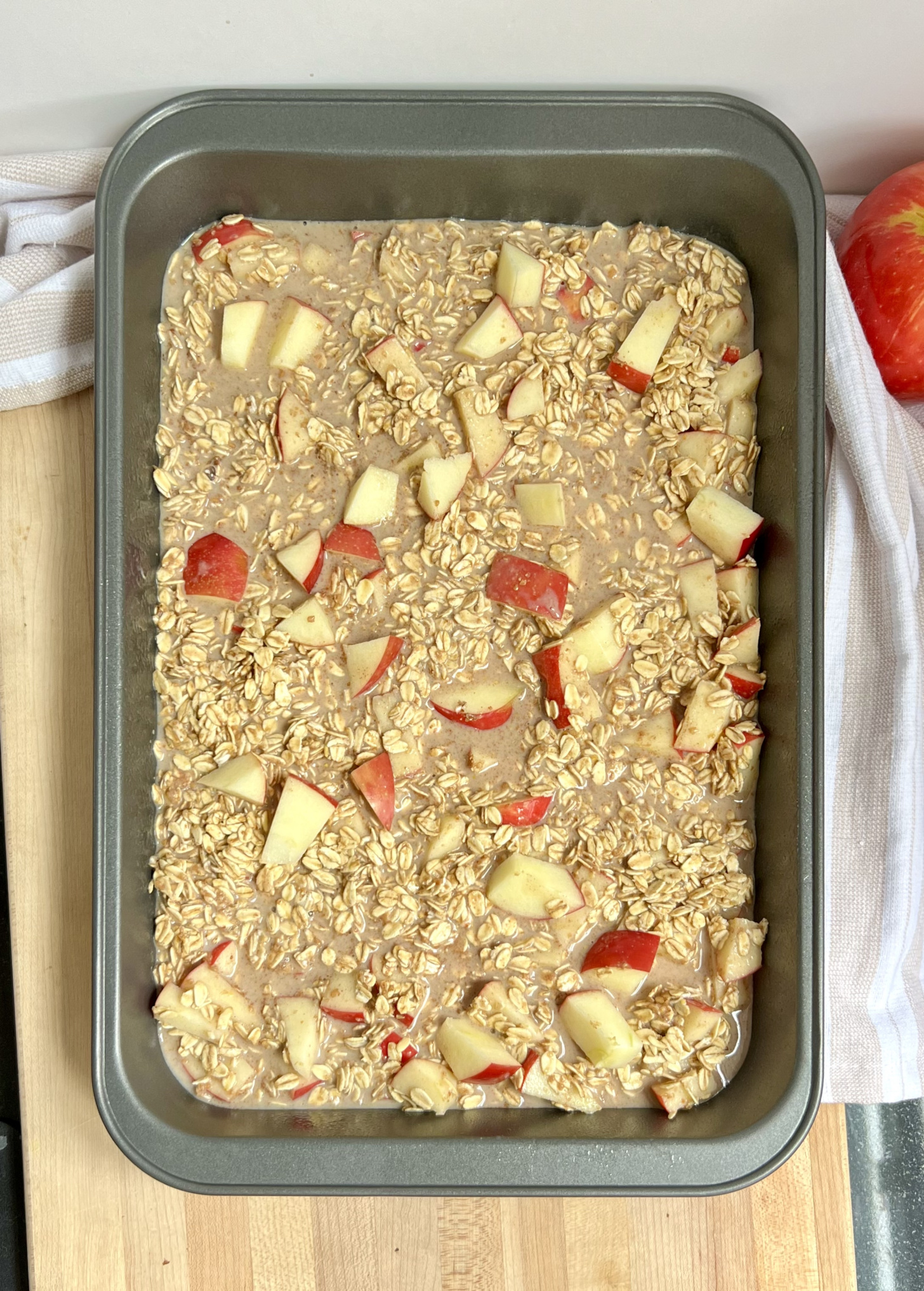 Large tray with uncooked oats and sliced apples inside.