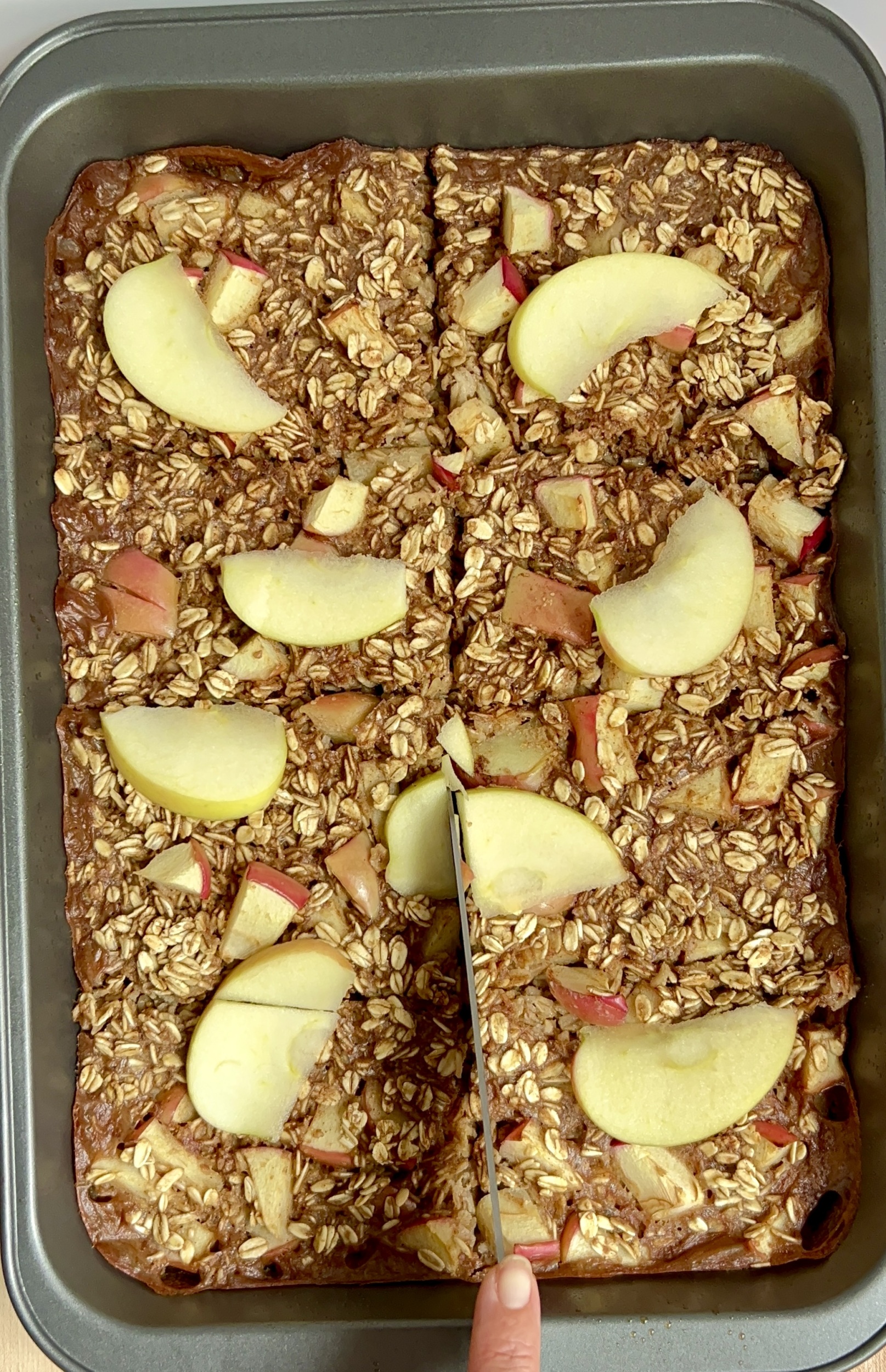 Large tray with baked oatmeal inside and a knife cutting slices.