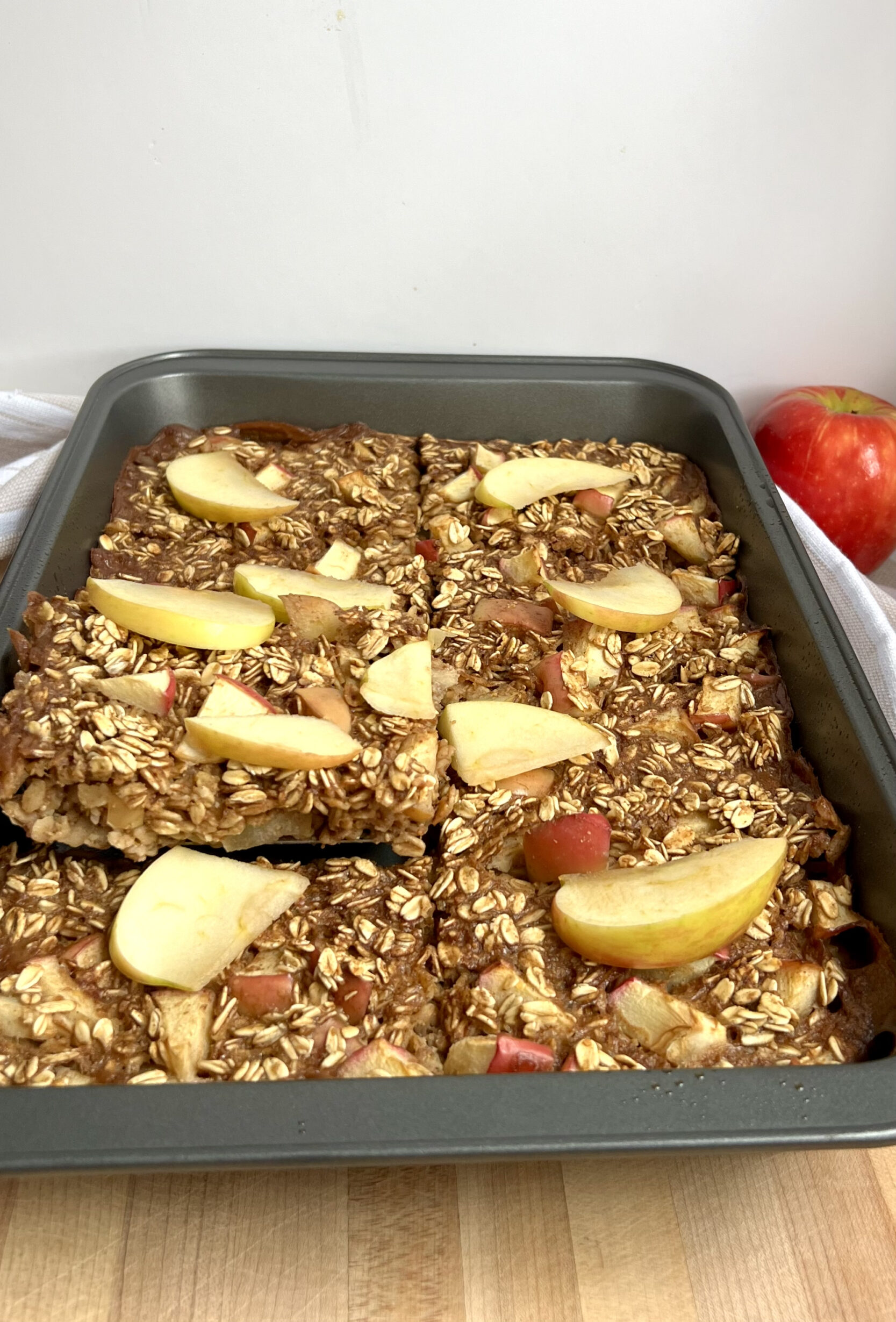 Large tray with baked oatmeal inside and a spatula taking out a slice.