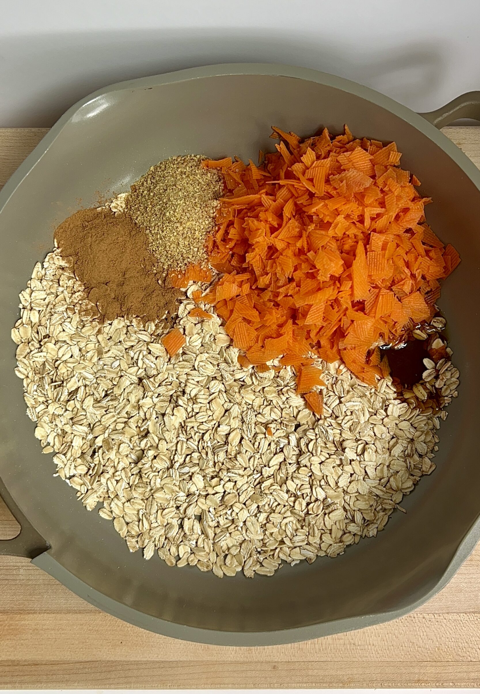 Pot with dried oats, grated carrot, flax, cinnamon, maple syrup, and vanilla.