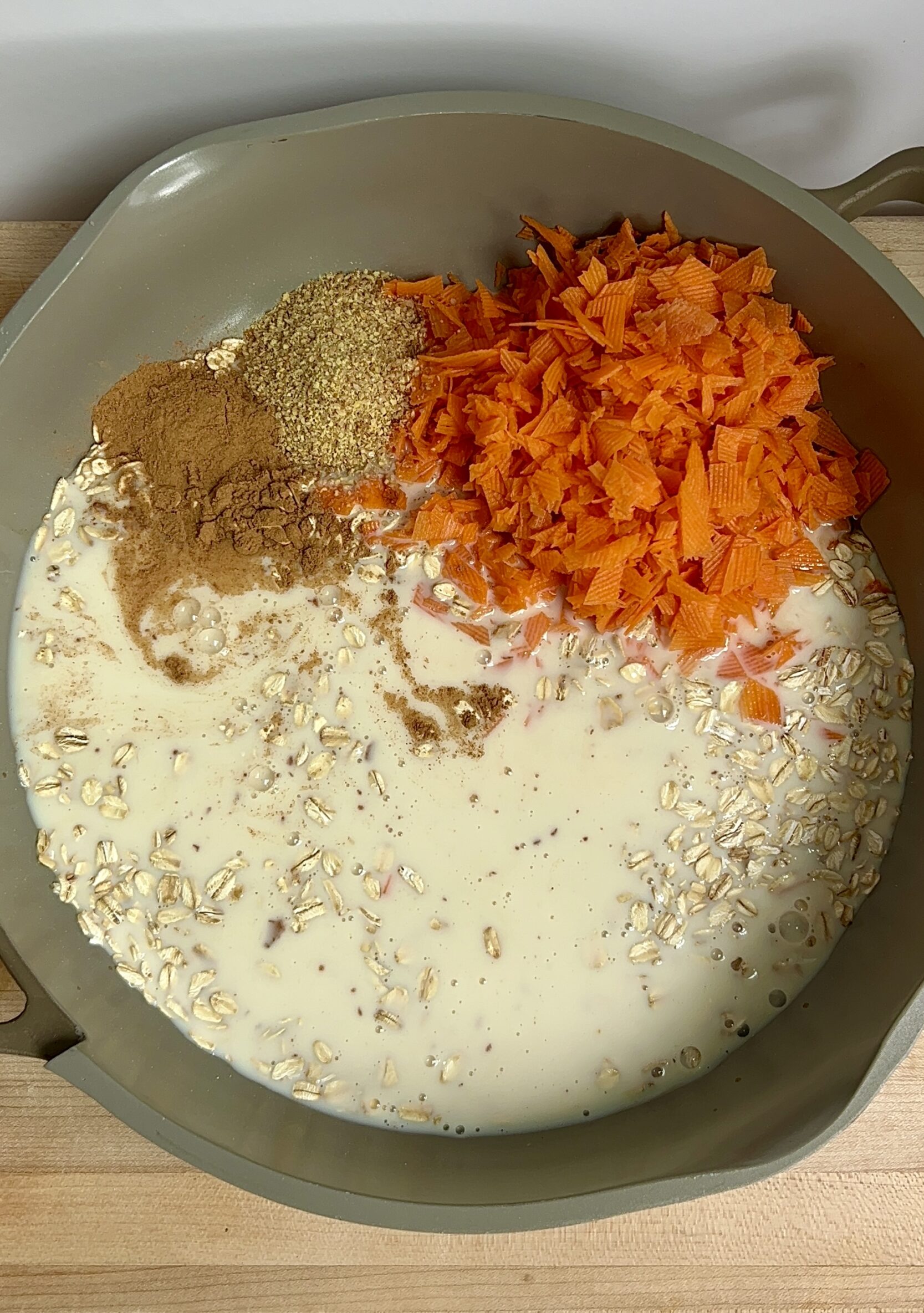 Pot with dried oats, grated carrot, flax, cinnamon, maple syrup, soy milk and vanilla.