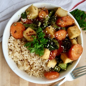 Bowl with sesame glazed tofu with sliced carrots and broccoli with rice.