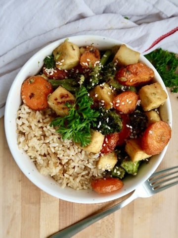 Bowl with sesame glazed tofu with sliced carrots and broccoli with rice.