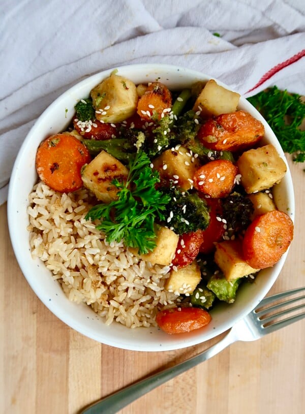 Bowl with sesame glazed tofu with sliced carrots and broccoli with rice.