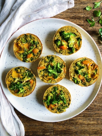 Plate of vegan egg bites with broccoli and bell peppers.