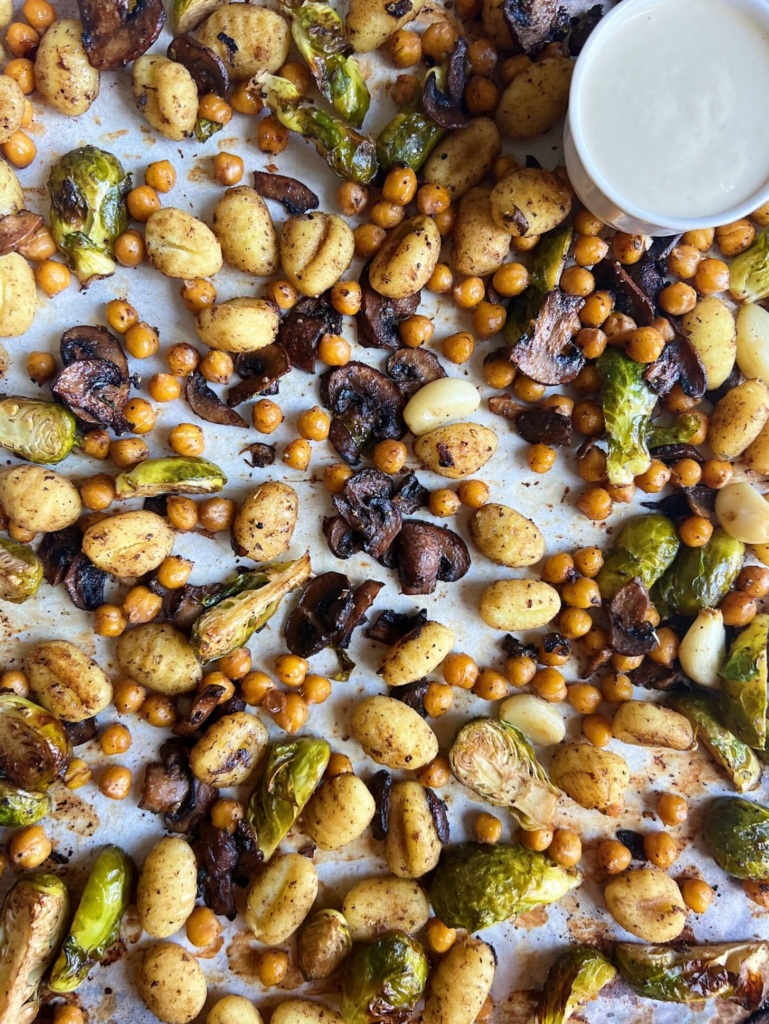 Cooked Chickpeas, brussel sprouts, and gnocchi and mushrooms on a sheet pan.