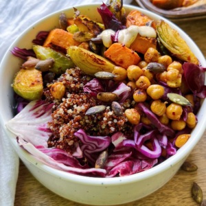 White bowl with roasted sweet potato, raddichio, chickpeas, quinoa and a tahini dressing.