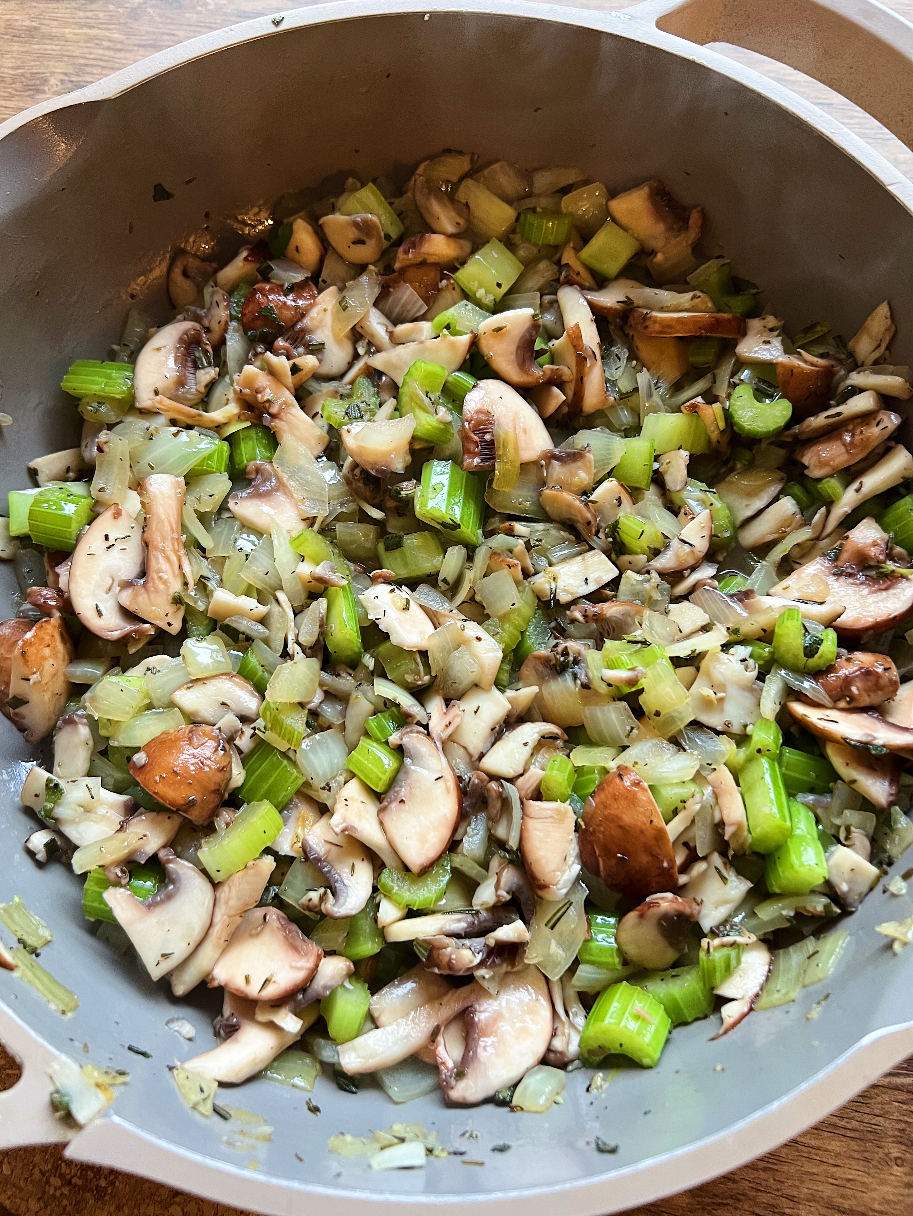 Mushrooms, onion and celery being cooked in a pan. 