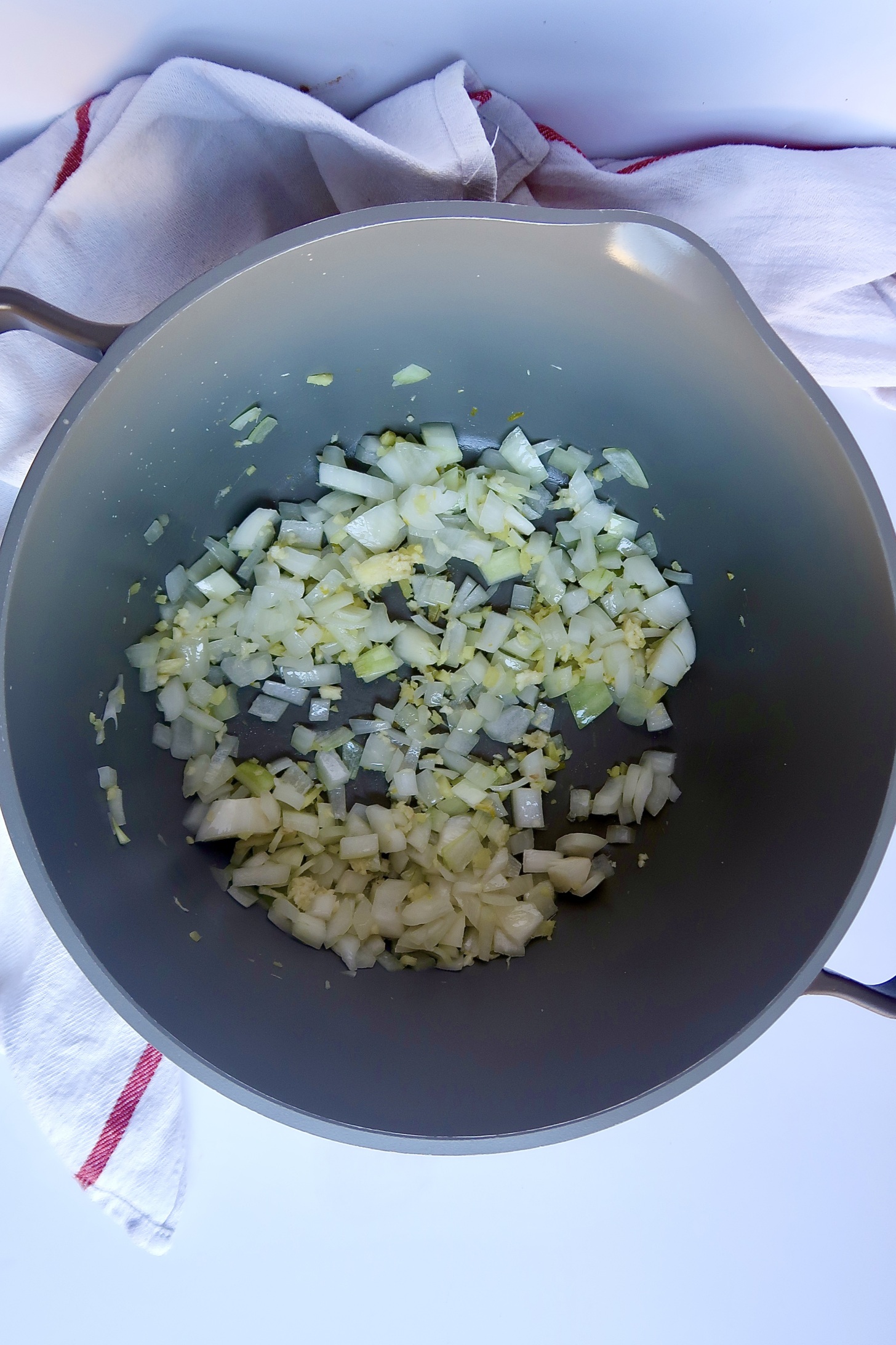 Large pot with sautéed onion and garlic inside.