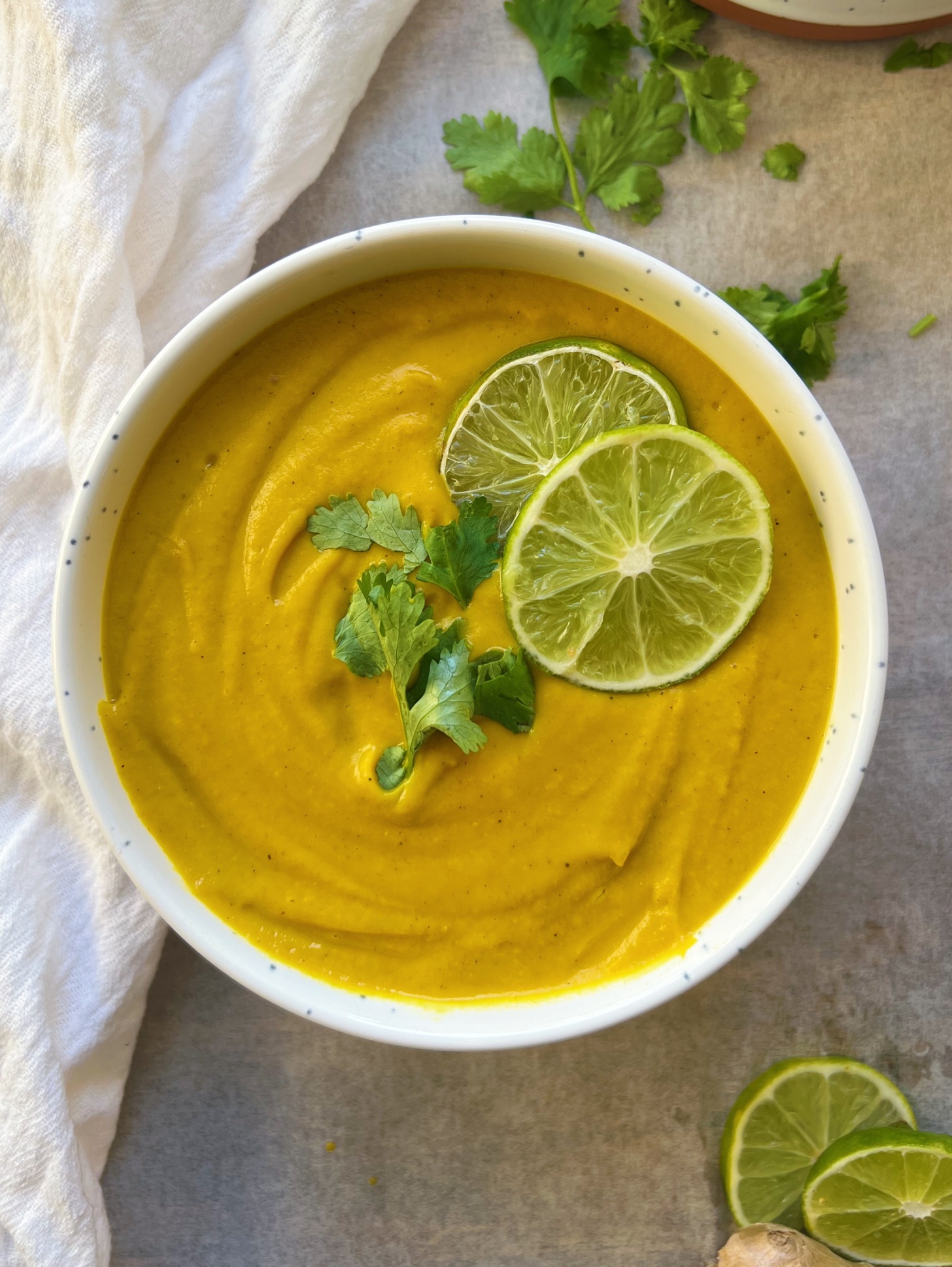 White bowl with a pureed carrot ginger soup inside.
