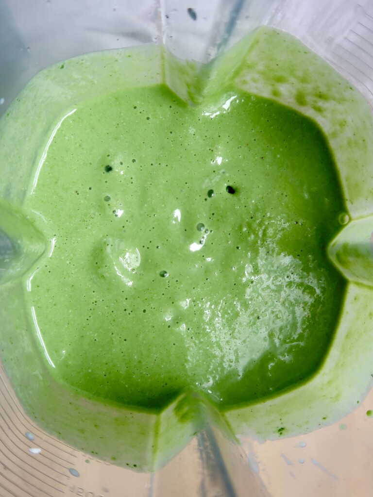 Blended green smoothie in a smoothie jug.