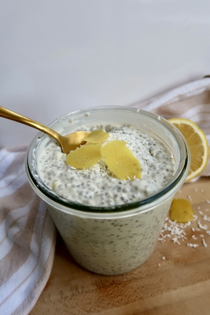Jar with chia pudding and lemon zest on top with a spoon in it.