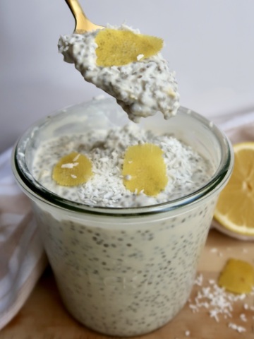 Jar with chia pudding and lemon zest on top with a spoon in it.