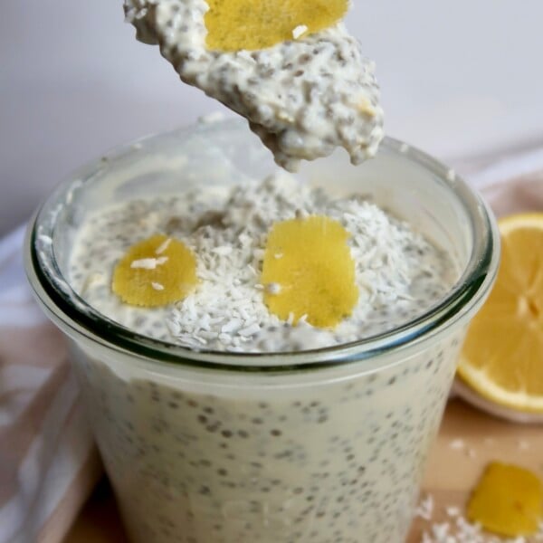Jar with chia pudding and lemon zest on top with a spoon in it.