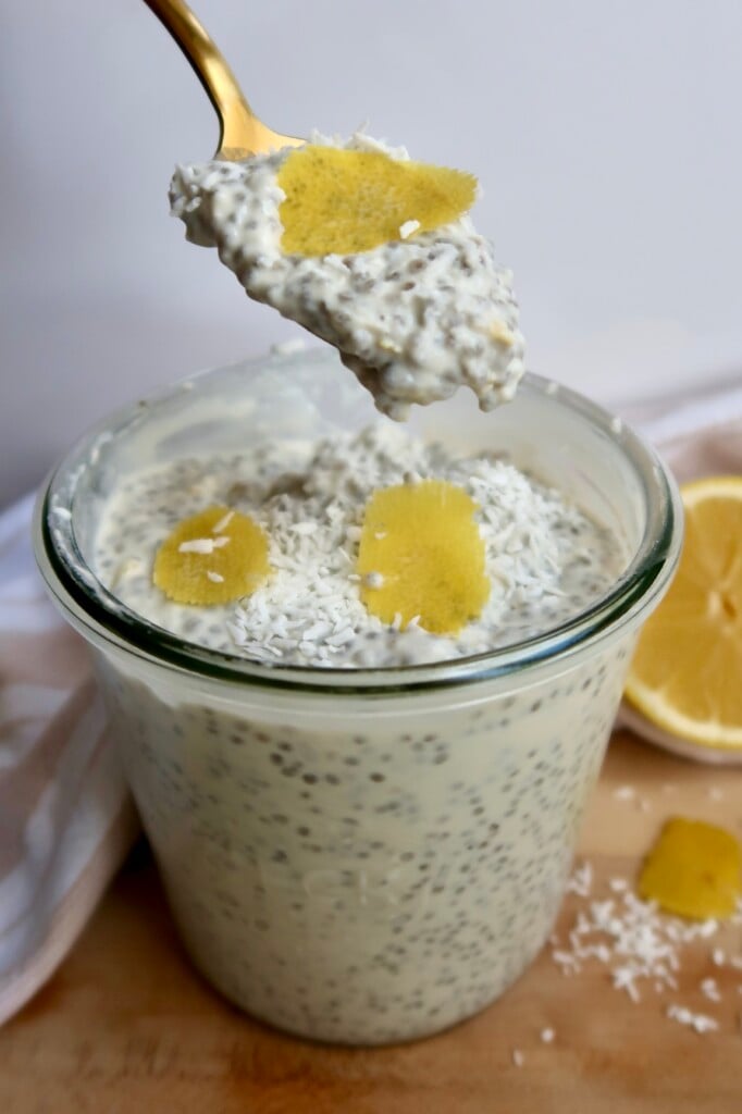 Jar with chia pudding and lemon zest on top with a spoon in it.