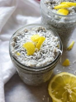White background with a mason jar of Lemon Coconut Chia Pudding with coconut flakes on top and lemon garnish.