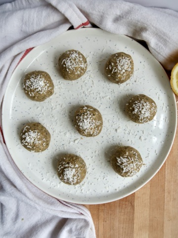 Lemon energy balls on a plate with coconut shreds on top.