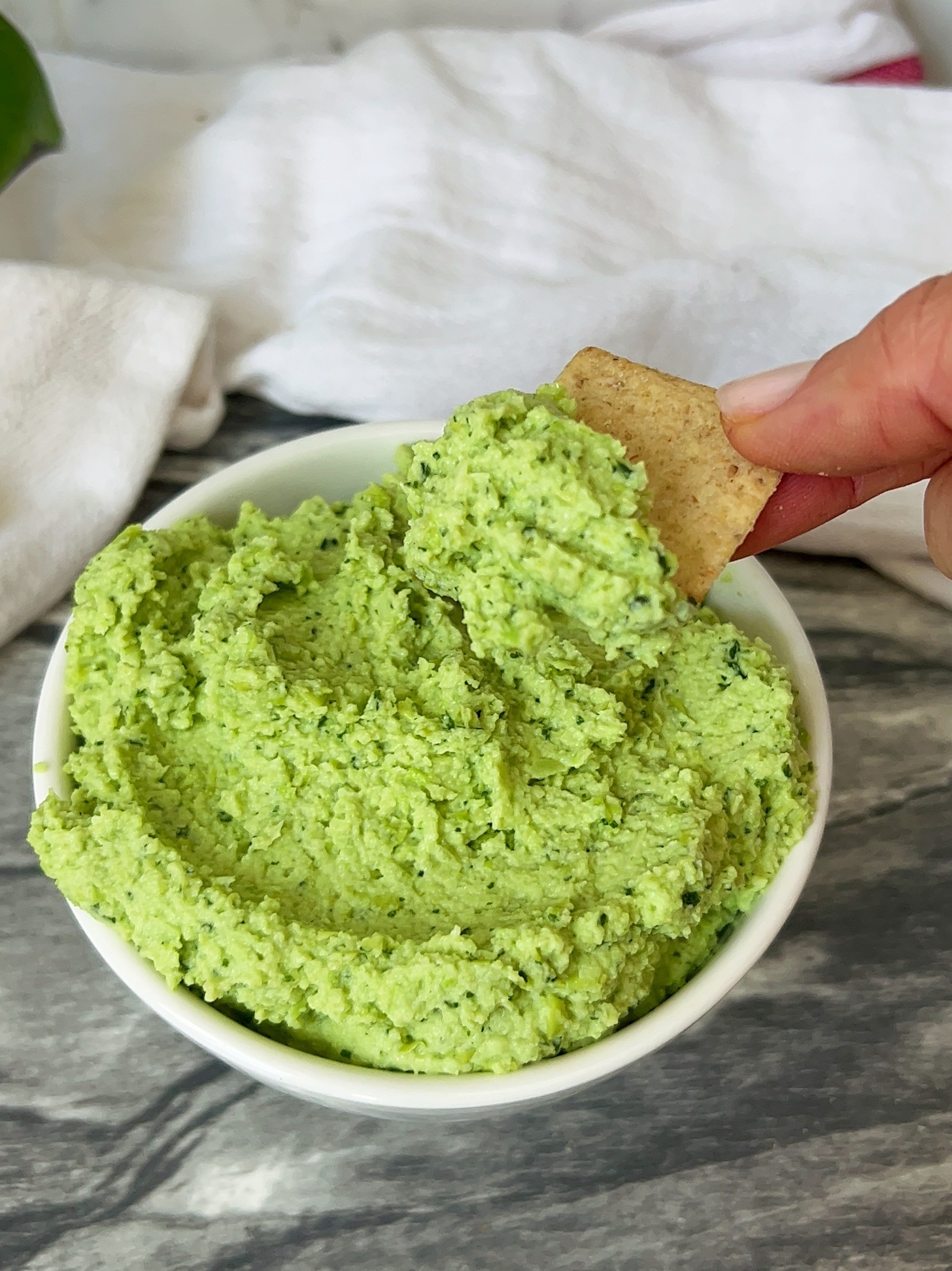 Bowl with cilantro lime dip and a cracker scooping some.