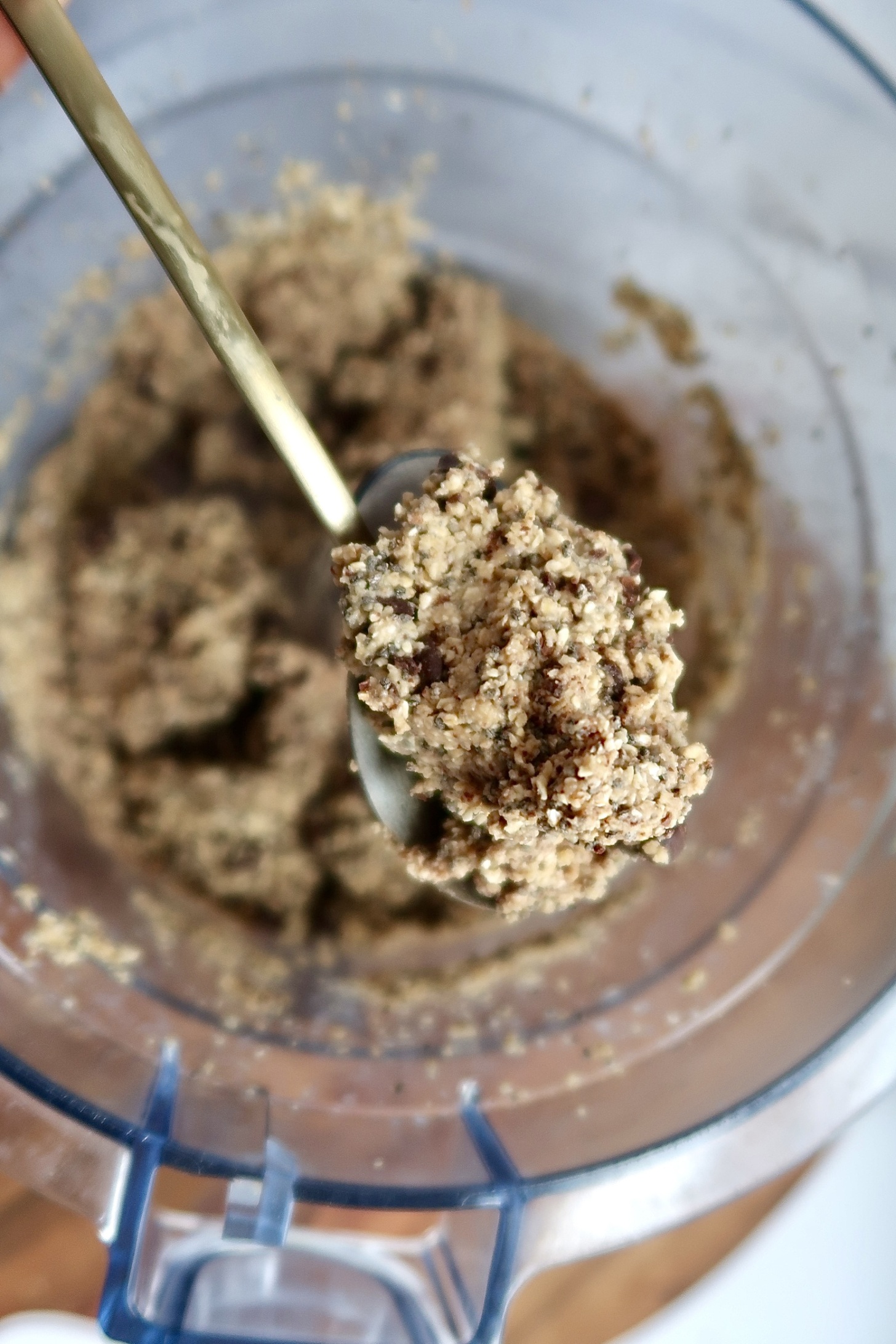 Food processor with energy bite dough and spoon scooping some of it.