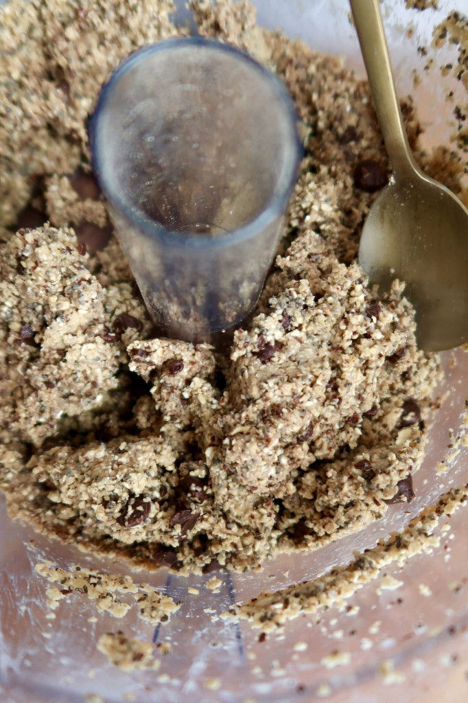 Food processor with energy ball dough and a spoon inside.