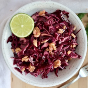 Cabbage salad in a bowl with walnuts and lime.