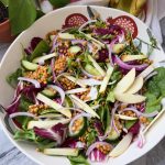 Large white bowl of salad with apple, red onion, lentils.