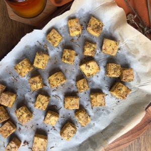 Sheet pan with parchment paper on top and baked rosemary thyme crispy tofu.