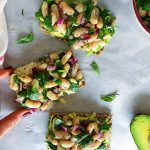 Three crackers with white bean and basil salad with an avocado on the side