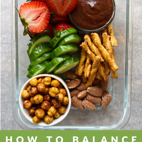 Vegan snack box lunch with strawberries, vegan nutella, pretzels, roasted chickpeas, almonds and cucumber in a glass container with the text how to balance blood sugar with a dietitian below.