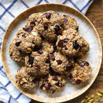 Plate with breakfast cookies filled with oats, nuts and chocolate chips, with a white and blue cloth in the background.