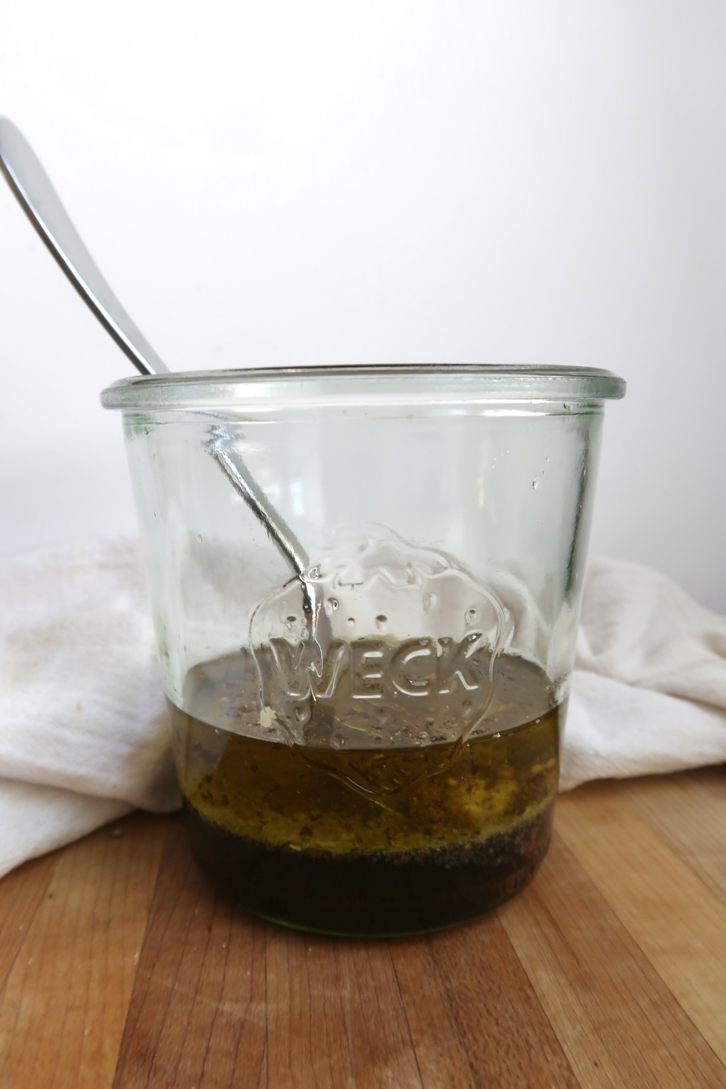 Jar with separated layers of oil and balsamic vinegar before mixing, spoon inside.