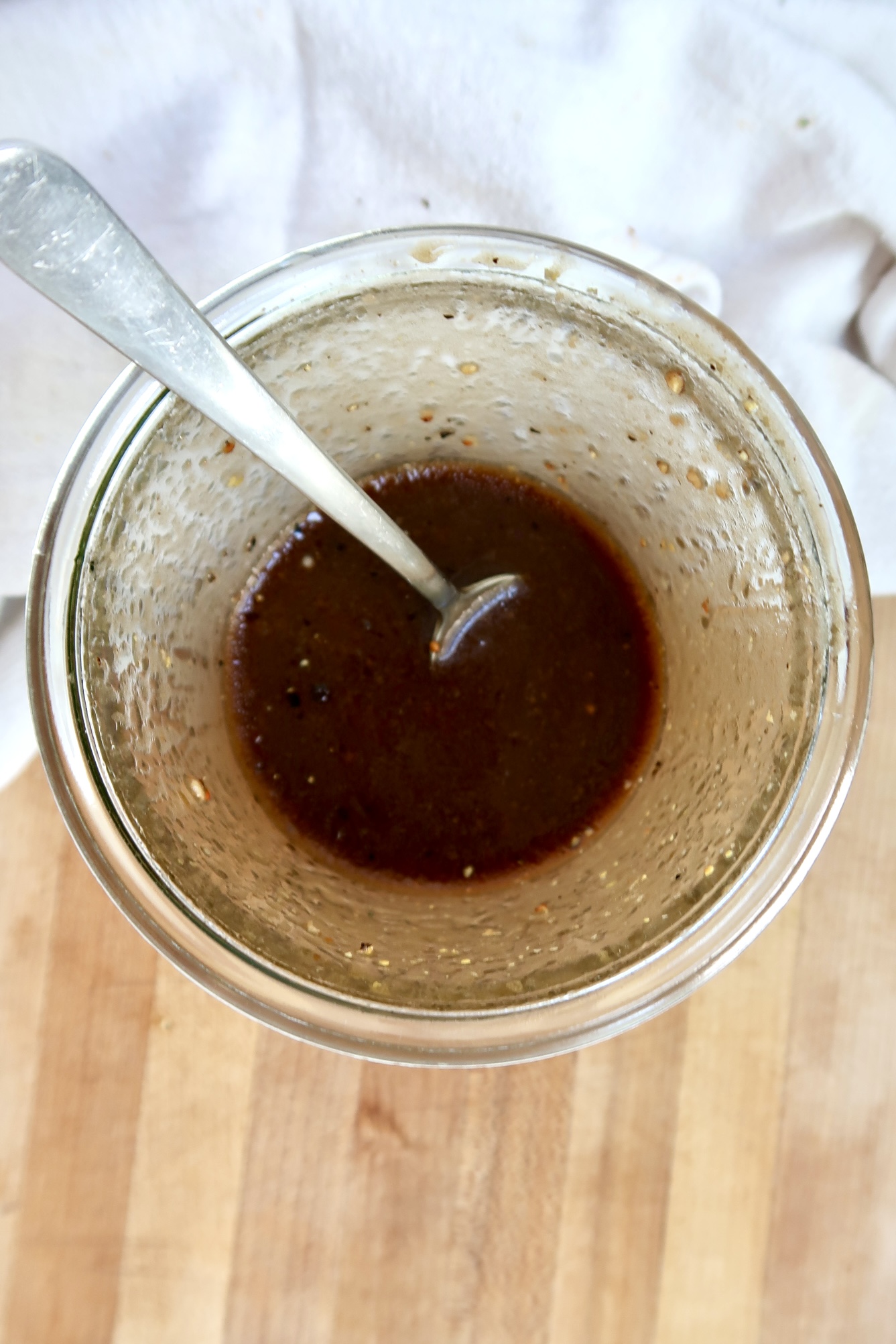 Top view of glass jar showing the dark vinaigrette mixture and spoon handle.