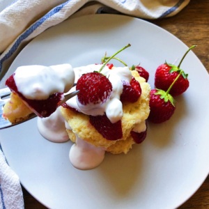 Plate with vegan strawberry shortcake on top with biscuits, strawberries and vegan whipped cream.