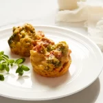 White plate with two sundried tomato broccoli egg bites on top.