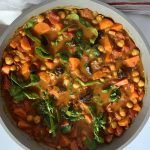 Pan of spiced chickpea stew with spinach mixed in.