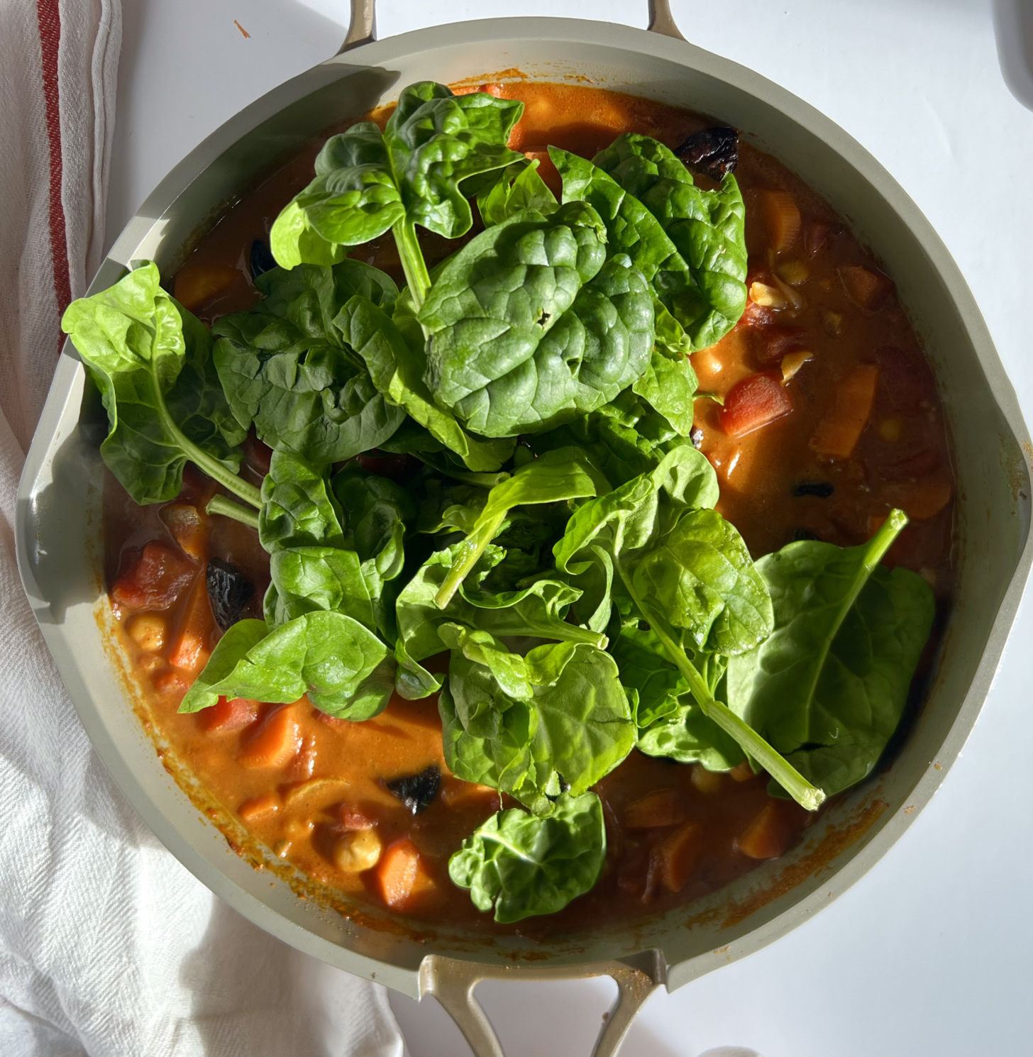 Pan with stewed chickpea curry with spinach on top.