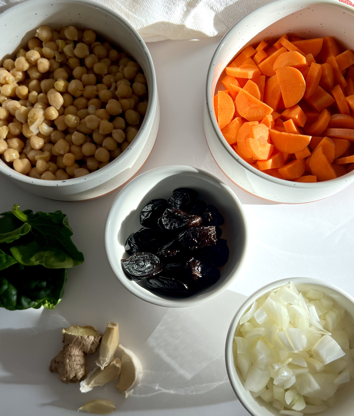 Ingredients to make the spiced chickpea stew with chickpeas, carrots, prunes, onion, garlic and spinach.