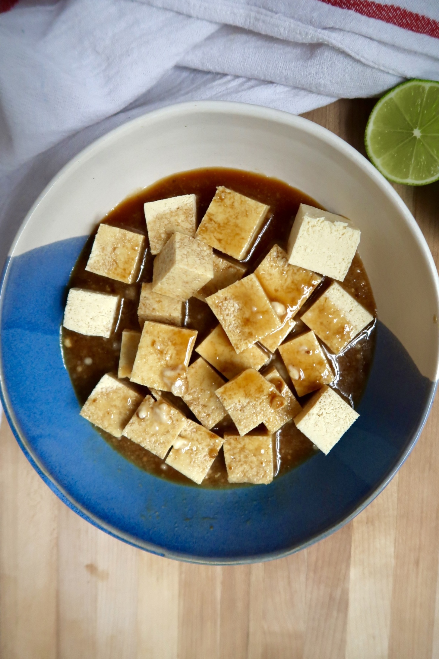 Bowl with cubed tofu in it and teriyaki stir fry sauce.