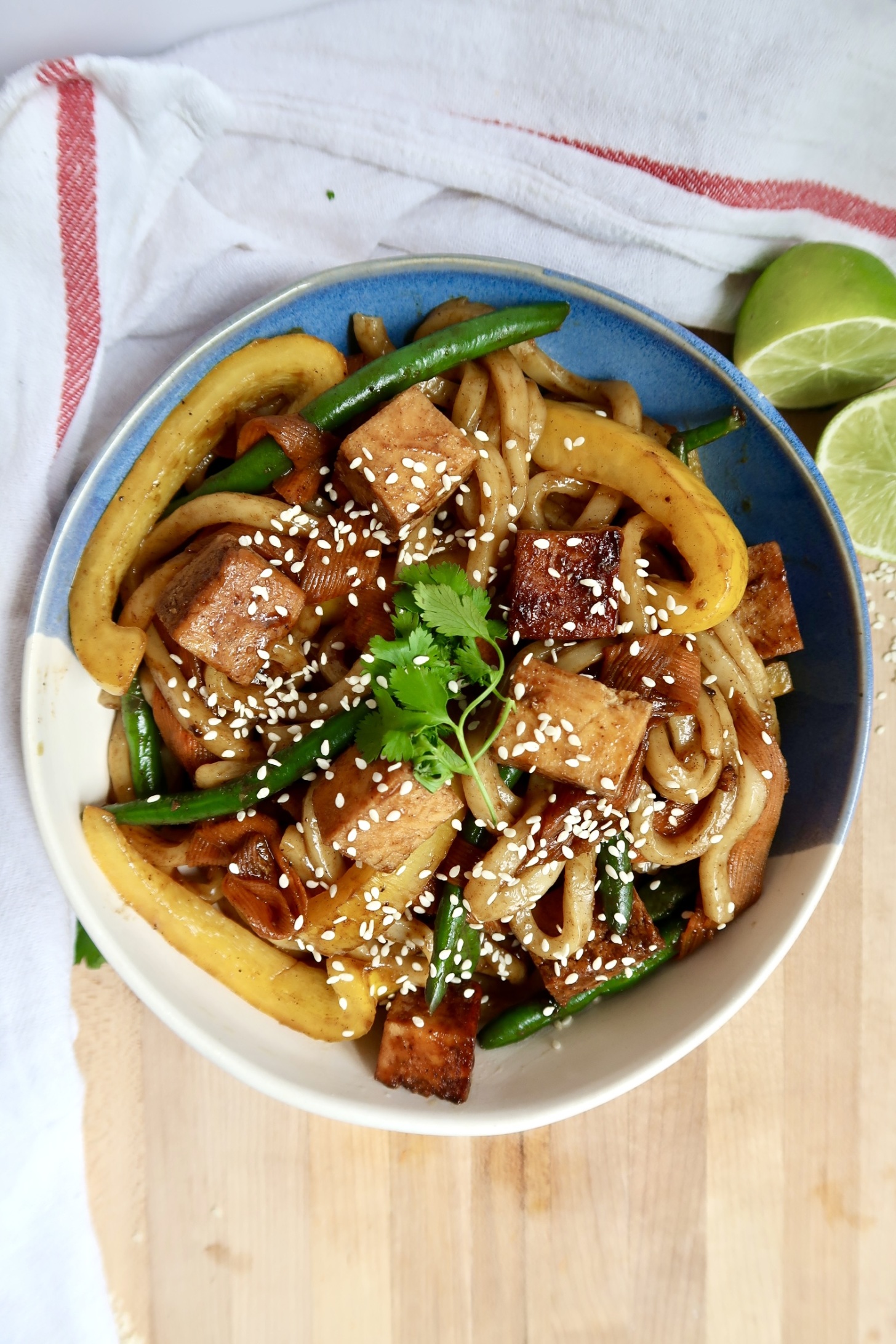 Bowl with teriyaki tofu udon noodle stir fry and veggies.
