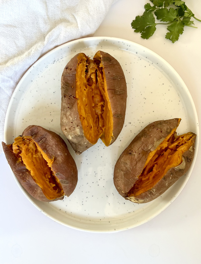 Three baked sweet potato on a white plate cut down the center