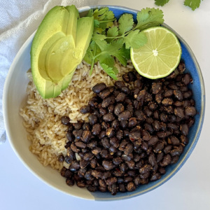 Black beans and rice in a bowl with avocado, lime and cilantro on the side