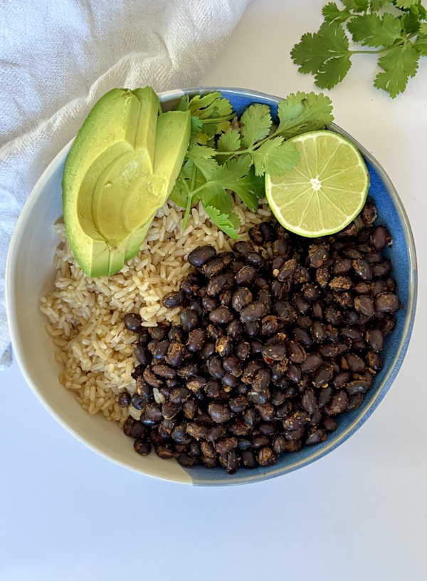 Black beans and rice in a bowl with avocado, lime and cilantro on the side