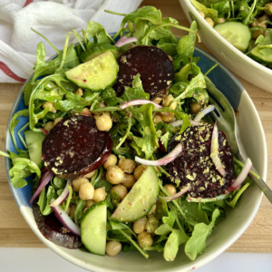 White and blue bowl with beet chickpea salad with a salad on the side.