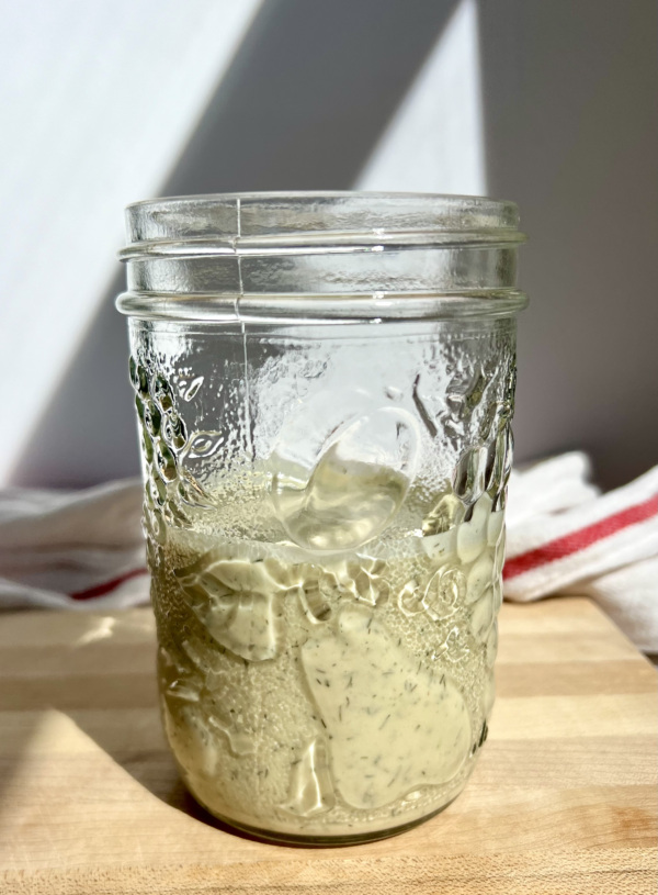 Salad dressing in a mason jar on top of a cutting board.