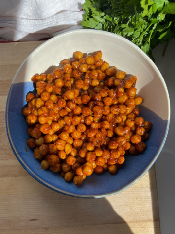 Chickpeas covered in BBQ sauce in a bowl with cilantro on the side.