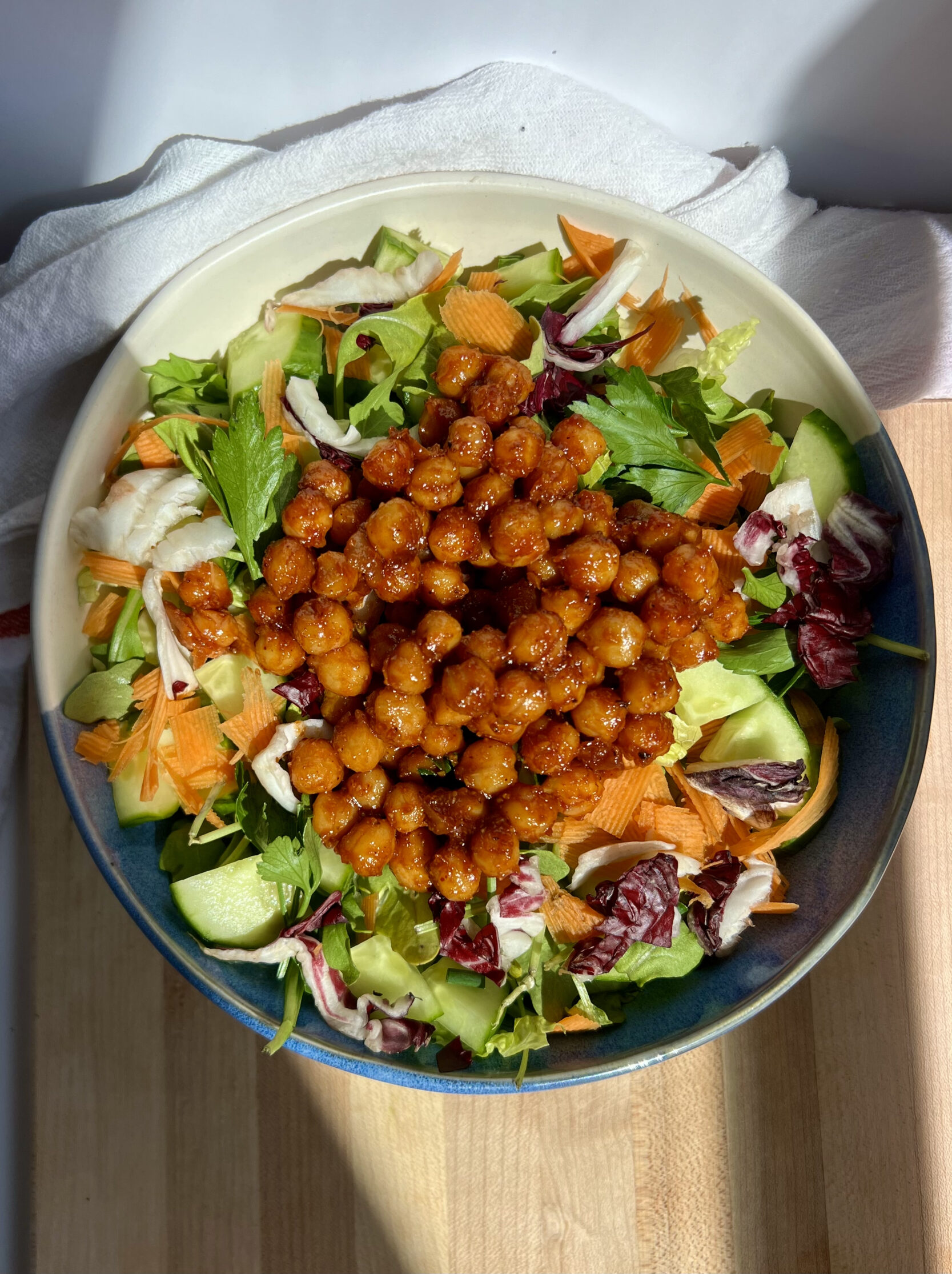White and blue bowl with chickpeas in BBQ sauce on top of veggies